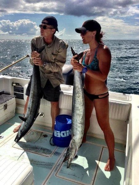 A man and woman with a double wahoo catch offshore